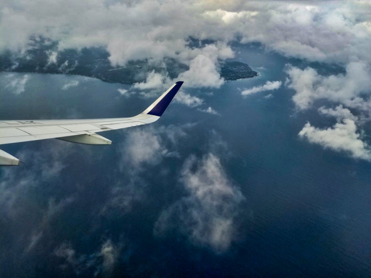 services-02 An airplane wing flying over the cloudy coastline of Aceh, Indonesia.